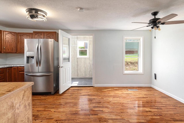 kitchen with stainless steel refrigerator with ice dispenser, a textured ceiling, wood-type flooring, and ceiling fan