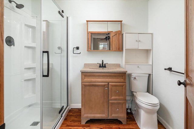 bathroom featuring vanity, toilet, hardwood / wood-style floors, and a shower with shower door