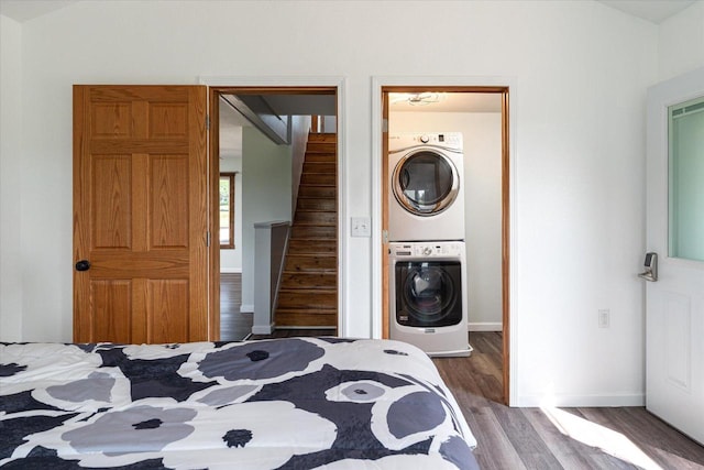 bedroom featuring wood-type flooring, stacked washer / dryer, and ensuite bathroom