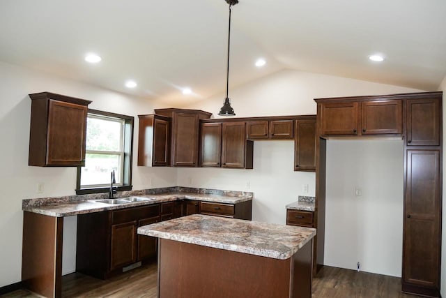 kitchen with sink, dark wood-type flooring, light stone counters, pendant lighting, and vaulted ceiling