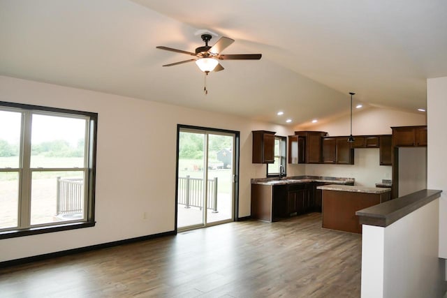 kitchen featuring decorative light fixtures, a kitchen island, a wealth of natural light, and lofted ceiling