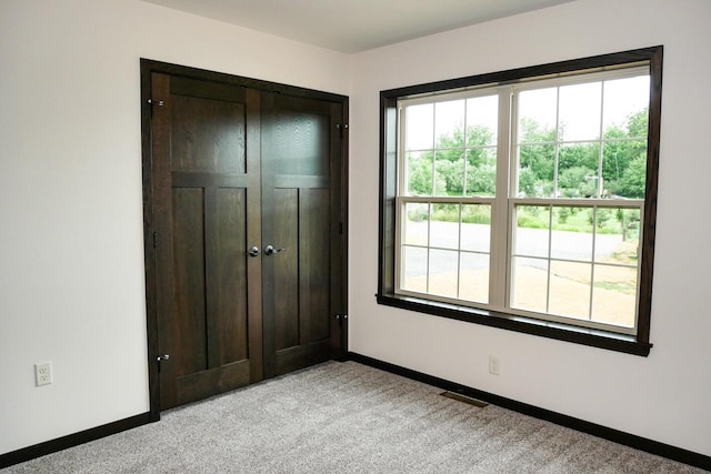 unfurnished bedroom with light colored carpet and a closet