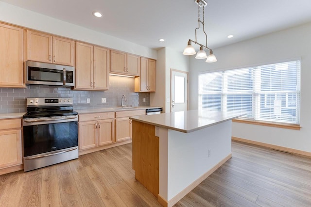 kitchen with light brown cabinetry, appliances with stainless steel finishes, hanging light fixtures, sink, and light wood-type flooring