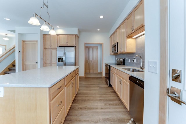 kitchen featuring a kitchen island, pendant lighting, light hardwood / wood-style floors, stainless steel appliances, and sink