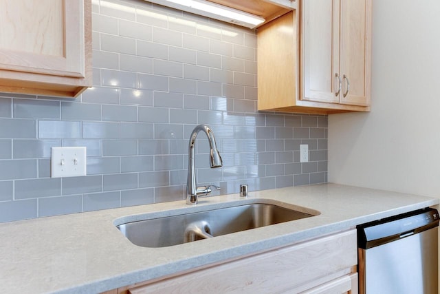 kitchen with light stone counters, stainless steel dishwasher, light brown cabinetry, and sink