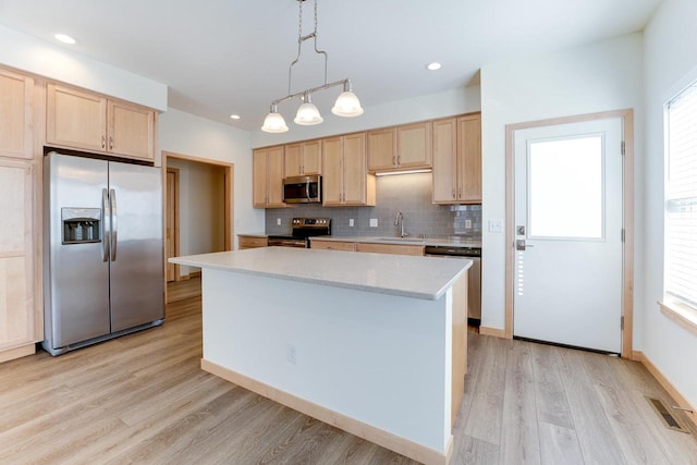 kitchen with light wood-type flooring, a wealth of natural light, a kitchen island, and stainless steel appliances