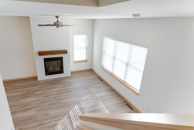 unfurnished living room with a fireplace, vaulted ceiling, ceiling fan, and light hardwood / wood-style floors