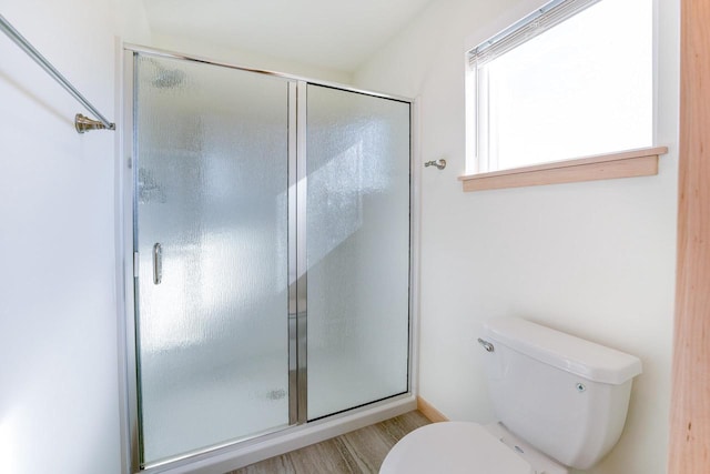 bathroom featuring hardwood / wood-style floors, toilet, and a shower with door