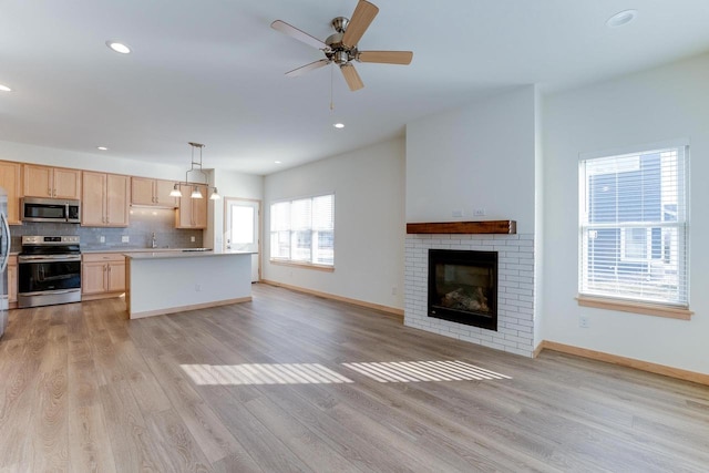 kitchen featuring decorative light fixtures, light hardwood / wood-style floors, stainless steel appliances, light brown cabinets, and ceiling fan