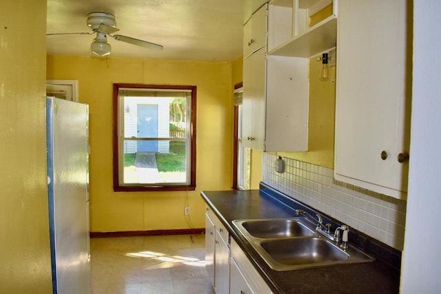 kitchen with white cabinetry, sink, stainless steel fridge, ceiling fan, and decorative backsplash