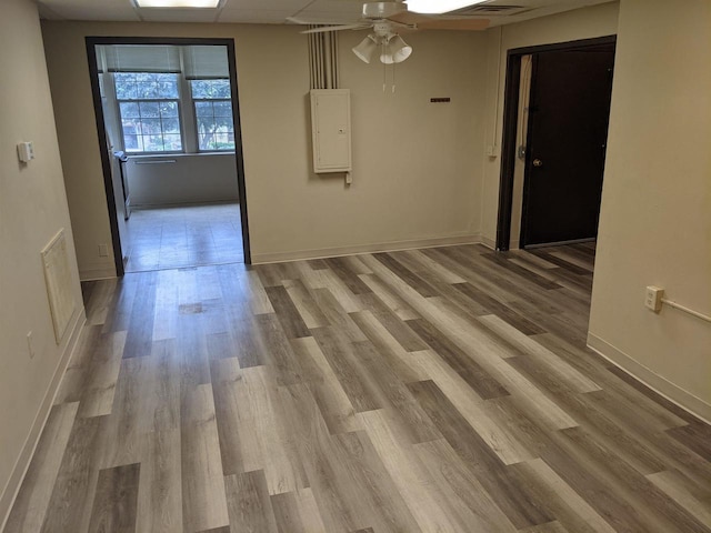 empty room with electric panel, light hardwood / wood-style flooring, and ceiling fan