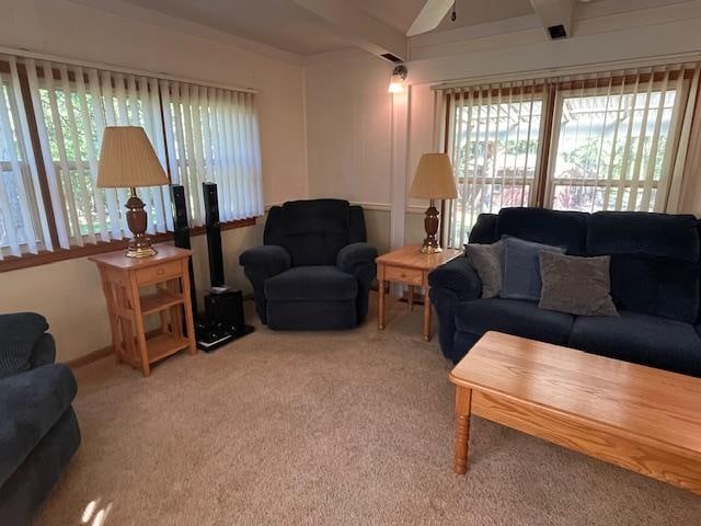 carpeted living room with beamed ceiling