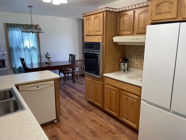 kitchen featuring white appliances, a chandelier, dark hardwood / wood-style floors, pendant lighting, and decorative backsplash