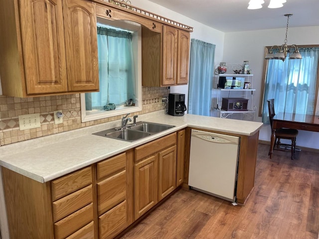 kitchen featuring dishwasher, hanging light fixtures, kitchen peninsula, dark wood-type flooring, and a chandelier