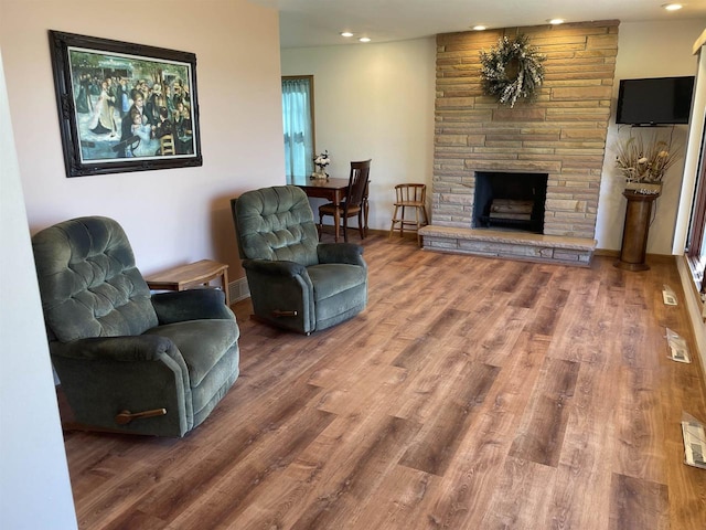 living room with wood-type flooring and a stone fireplace