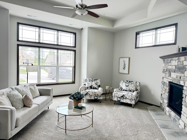 living room featuring a fireplace, light carpet, and ceiling fan