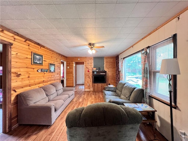 living room featuring ceiling fan, wood walls, and hardwood / wood-style floors