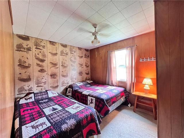 carpeted bedroom with ceiling fan and wooden walls