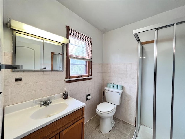 bathroom with tile walls, vanity, toilet, and a shower with shower door