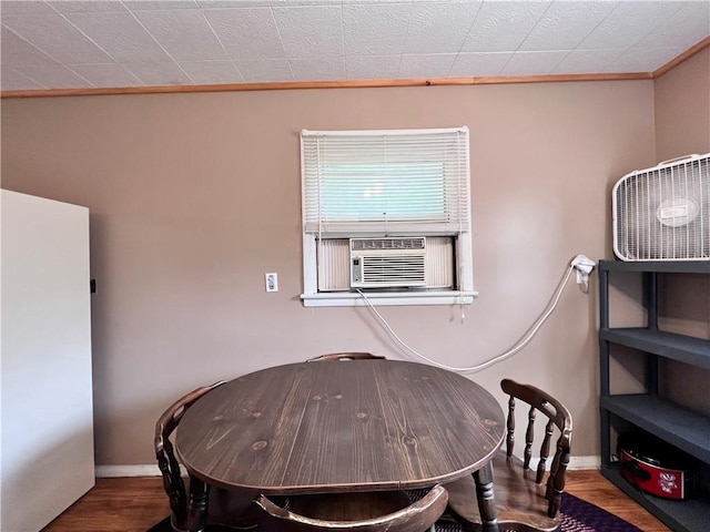 dining area featuring cooling unit, ornamental molding, and wood-type flooring