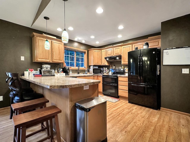 kitchen with pendant lighting, light hardwood / wood-style flooring, black appliances, kitchen peninsula, and a breakfast bar area