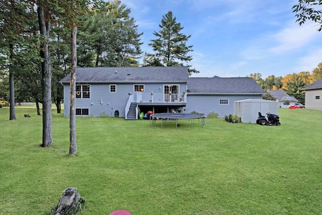 back of house featuring a trampoline, a lawn, a storage unit, and a deck