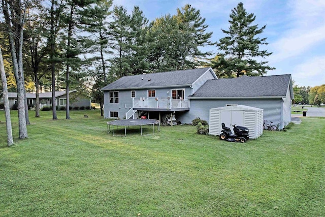 rear view of property featuring a trampoline, a lawn, and a storage unit