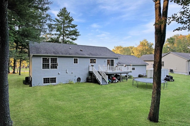 rear view of house featuring a yard, a trampoline, a deck, and central air condition unit