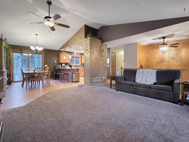 living room featuring lofted ceiling, ceiling fan with notable chandelier, and hardwood / wood-style flooring