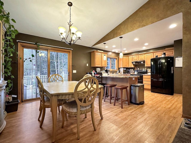 dining room featuring vaulted ceiling, light hardwood / wood-style flooring, and a notable chandelier