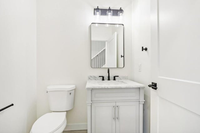 half bath with vanity, toilet, and baseboards