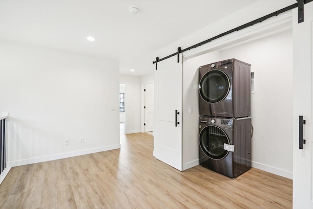 317 Maple St, Pardeeville, WI 53954 - clothes washing area featuring a barn door, stacked washing machine and dryer, light wood finished floors, baseboards, and recessed lighting