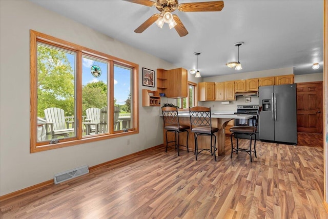 kitchen with visible vents, light countertops, light wood-style flooring, appliances with stainless steel finishes, and a peninsula