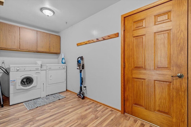 laundry area featuring washing machine and dryer, cabinet space, light wood-style flooring, and baseboards