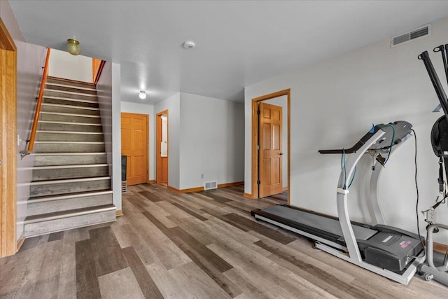 exercise room featuring visible vents, baseboards, and wood finished floors