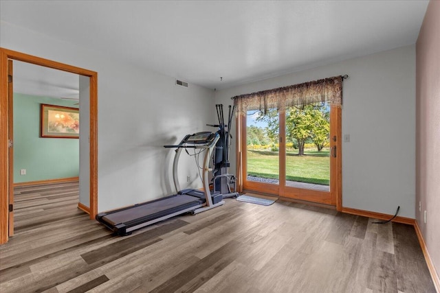 exercise area featuring wood finished floors, visible vents, and baseboards