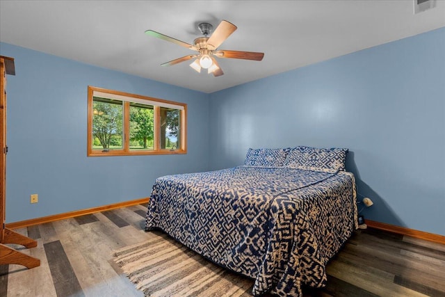 bedroom with visible vents, baseboards, wood finished floors, and a ceiling fan