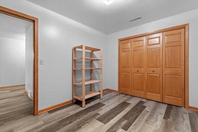 unfurnished bedroom with wood finished floors, visible vents, and baseboards