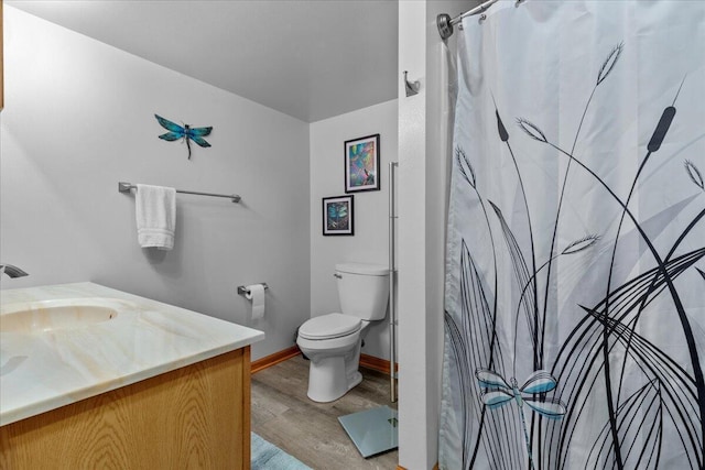 bathroom with toilet, curtained shower, wood finished floors, baseboards, and vanity