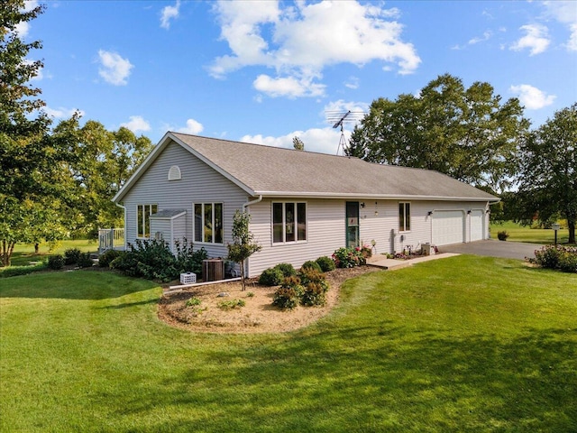 view of front of home with a front yard, central AC, an attached garage, and driveway