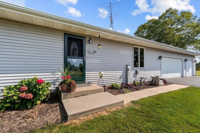 view of exterior entry with aphalt driveway and an attached garage