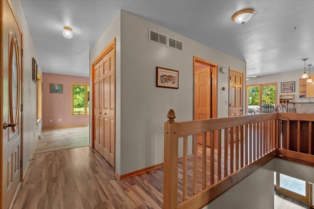 corridor with an upstairs landing, visible vents, and a wealth of natural light