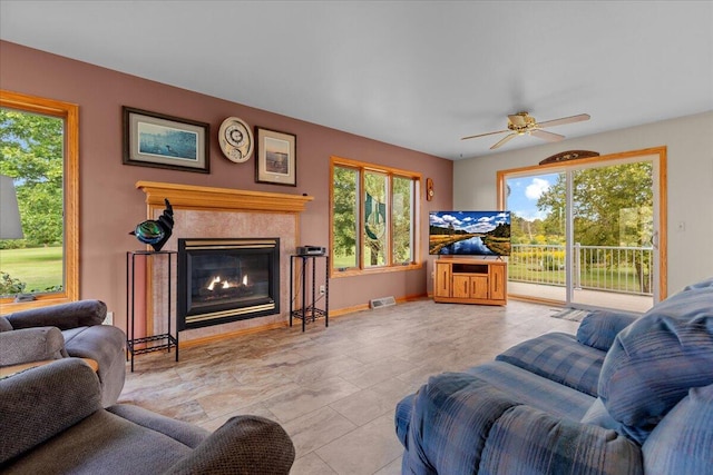 living room with a premium fireplace, baseboards, visible vents, and ceiling fan