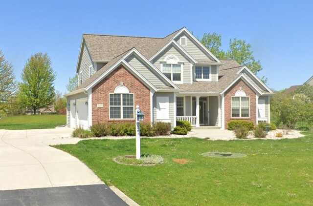 view of front facade featuring a garage, a front lawn, and covered porch