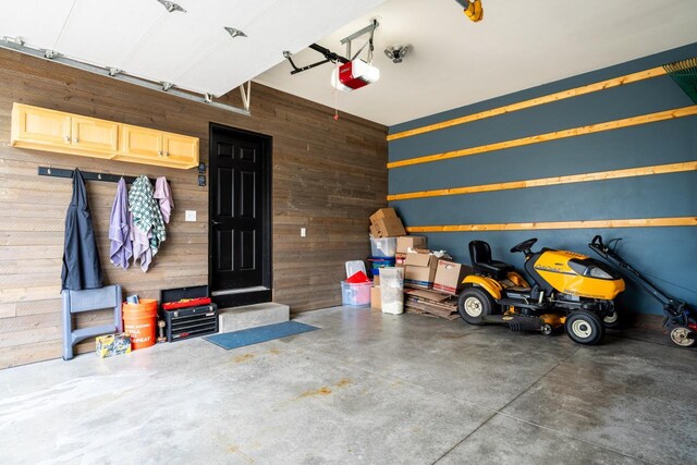 garage featuring a garage door opener and wooden walls