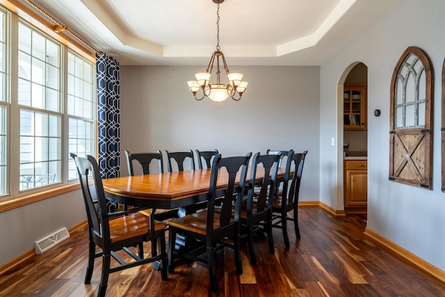 dining room with a raised ceiling, a chandelier, and dark hardwood / wood-style flooring