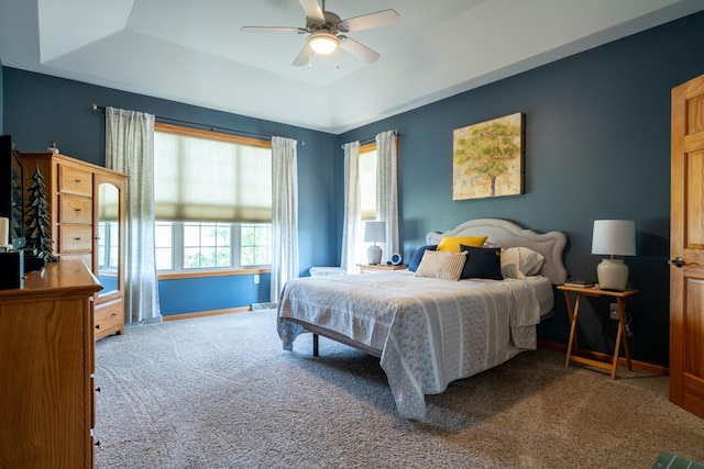 carpeted bedroom featuring a tray ceiling and ceiling fan