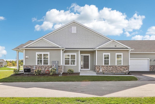 craftsman-style house with central air condition unit, a front yard, and a garage