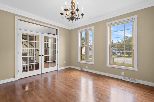 empty room with crown molding, a healthy amount of sunlight, hardwood / wood-style floors, and french doors