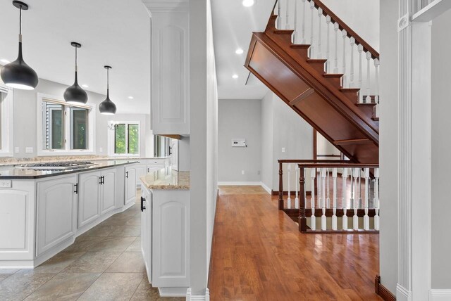 kitchen with light stone countertops, pendant lighting, stainless steel appliances, sink, and white cabinetry